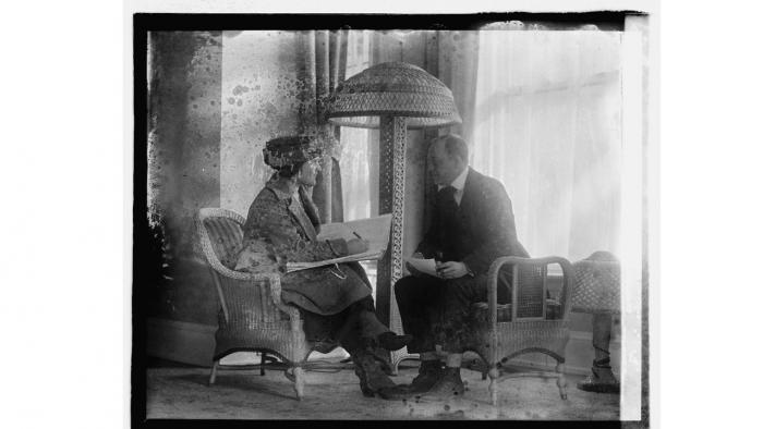 1920 female census enumerator sits next to a man and writes down his responses to the 1920 census