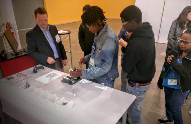 Dan Hartman (left) shows Chicago students how to assemble parts via video projection equipment